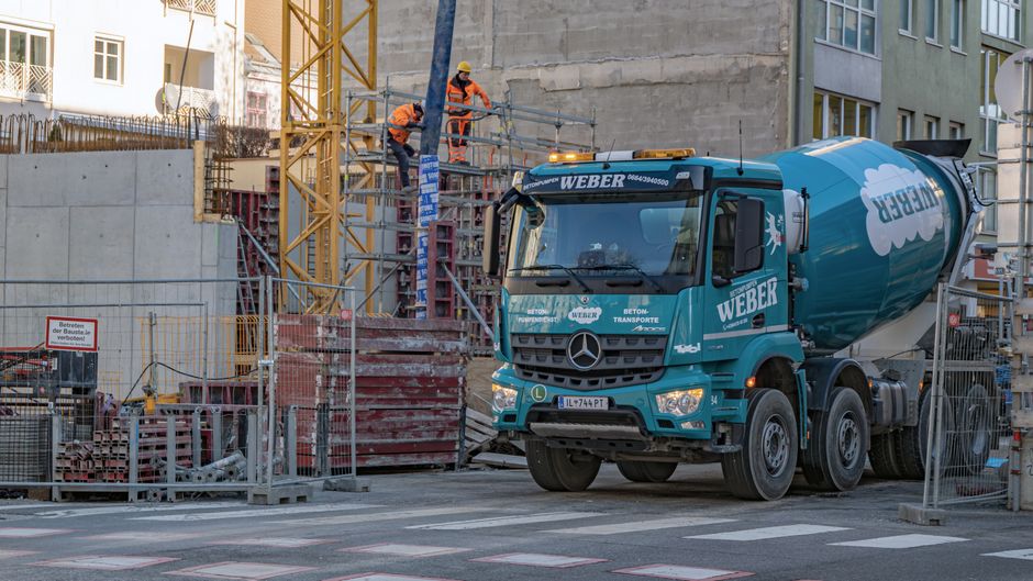 Urban construction site with cement mixer truck and workers in safety gear.